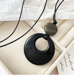 Detailed close-up of a minimalist agate pendant necklace on a beige suede gift box