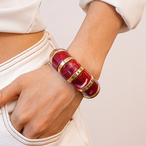 Close-up of geometric acrylic bangle with red marble texture and gold metal accents