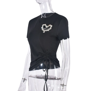 Détail d'un t-shirt noir avec cœur en strass argentés et cordon de serrage plissé sur le côté