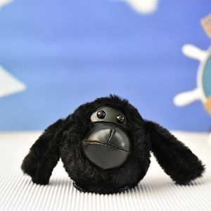 Primo piano di un portachiavi a forma di gorilla in peluche nero con dettagli viso