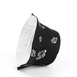 Détail du bob réversible avec imprimés papillons blancs sur toile de coton noire durable