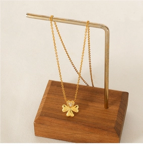 Close-up of golden four-leaf clover heart pendant necklace with tiny zircon inlays