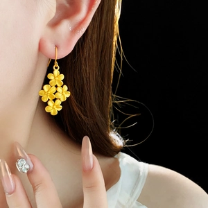 Détail macro de boucles d'oreilles fleurs plaquées or 18 carats avec finition mate sur modèle