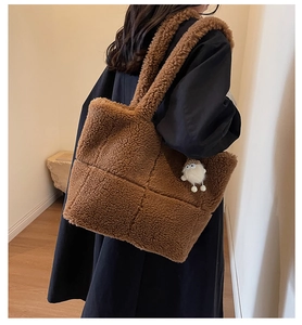 Detail einer braunen Teddy-Tote-Bag mit quadratischer Steppung und weißem Plüsch-Anhänger