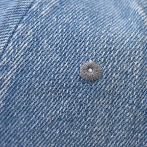 Close-up of blue washed denim texture with detailed grey embroidered ventilation eyelets