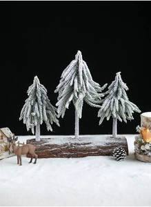 Miniature snow-covered trees set on a rustic wooden base for winter holiday decor