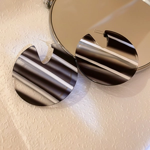 Detail of acrylic hoop earrings featuring bold black and white stripes and C-shaped design