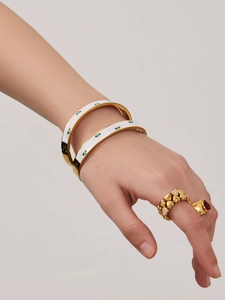 Detailed close-up of gold-plated evil eye bangles and heart rings on model hand