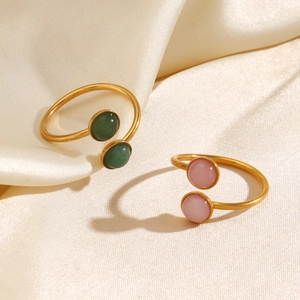 Minimalist gold open rings with pink and green circular gemstones on white silk