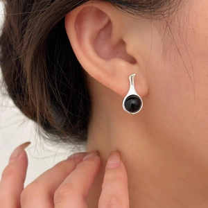 Close-up of minimalist sterling silver earring with round black onyx on a model