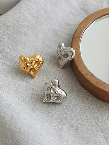 Detailansicht der herzförmigen Ohrringe mit gehämmerter Metallstruktur in Gold und Silber