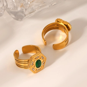 Macro shot of gold star-patterned open rings with green stones and white cubic zirconia