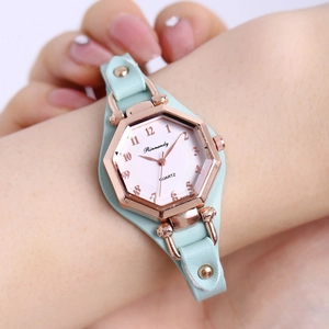 Détail d'une montre quartz hexagonale or rose avec bracelet en cuir vert clair au poignet