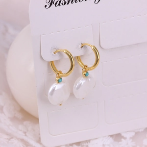 Close-up of golden hoop earrings with baroque pearl and turquoise bead on white background