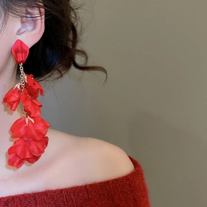 Macro shot of large red silk petal tassel earrings on model for festive elegant looks