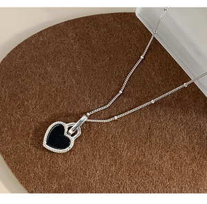 Macro shot of silver heart pendant necklace with black shell inlay on brown felt surface