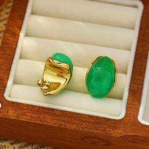 Detailed close-up of vintage gold earrings with oval green stones on velvet display