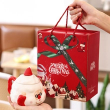 Close-up of Santa Claus ceramic mug with matching red Merry Christmas gift bag and handle