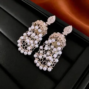 Elegant gold pearl tassel earrings with diamond accents on luxury black leather surface
