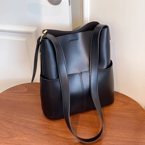 Minimalistische schwarze Eimer-Tasche aus Leder mit breitem Gurt und goldener Hardware