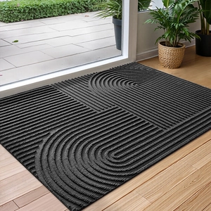 Detail of black rectangular door mat with geometric curved pattern on wooden floor