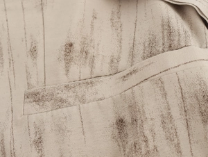 Vista macro del tessuto intrecciato beige a righe marroni con dettaglio tasca a filetto
