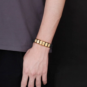 Detailed view of men's braided leather bracelet with golden charms on a wrist