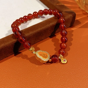 Detail of red garnet gourd bracelet with gold diamond charms on leather texture
