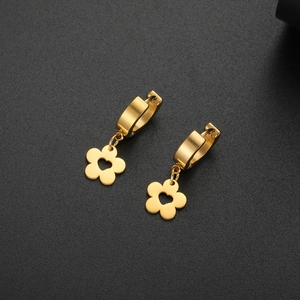Close-up of golden floral hoop earrings with heart cutouts on a textured background
