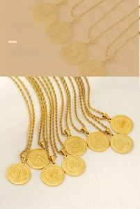 Detail of 18K gold-plated zodiac coin pendants with embossed symbols on twisted rope chains