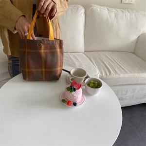 Close-up of vintage wool plaid lunch tote with yellow fabric handle and metal snap button