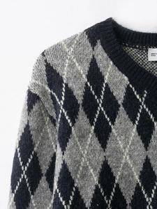 Close-up of classic argyle pattern on navy and grey long sleeve knit sweater