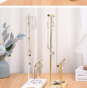 Detail view of T-shaped jewelry stands in gold and white with natural wooden bases