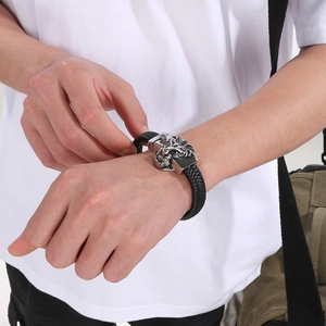 Detailed view of men's braided leather bracelet featuring a steel lion head buckle