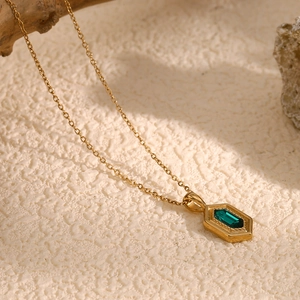Macro detail of emerald-cut green stone in a hexagonal gold-plated stainless steel pendant