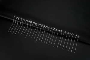 Macro shot of silver S925 sterling silver letter tassels on black leather texture