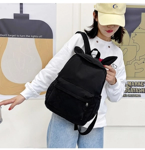 Model wearing a black canvas backpack featuring cute bunny ears and a C-letter patch