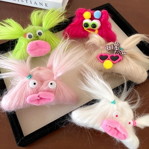 Close-up of five colorful plush monster hair clips with big eyes and thick lips on a tray