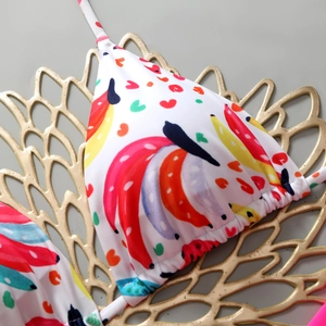 Detail of triangle bikini top with colorful banana and heart prints and ruffled hem