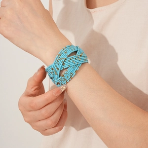 Détail d'un bracelet enveloppant multicouche bohème en perles bleu ciel et or au poignet