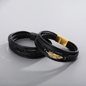 Detail view of woven leather bracelets with gold and black feather charms and metal clasps