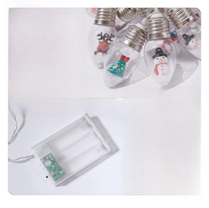 Macro detail of LED Christmas bauble lights featuring mini holiday scenes and battery box