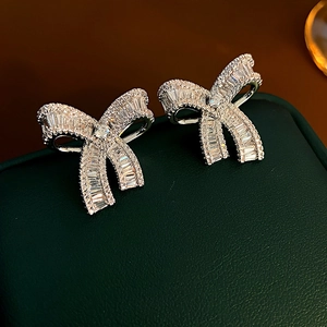 Macro shot of silver bow earrings featuring trapezoid and round cut pavé diamonds