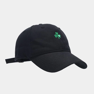Detail shot of green clover embroidery on black cotton twill baseball cap fabric