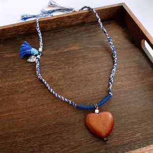 Ethnic woven necklace featuring a polished heart-shaped wood pendant and blue tassels