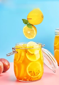 Close-up of glass storage jar with metal buckle lid featuring lemons and passion fruit