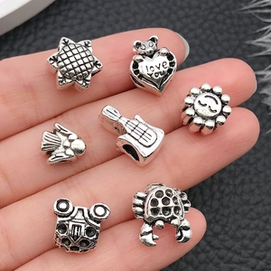 Close-up of vintage silver alloy beads in various shapes held in hand for DIY jewelry