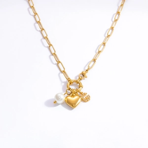 Detail of gold paperclip chain necklace with pearl heart and crystal G charms