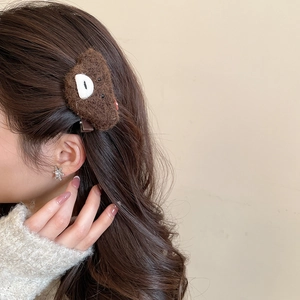 Close-up of a cute dark brown plush bear hair clip worn on model's hair for autumn styling