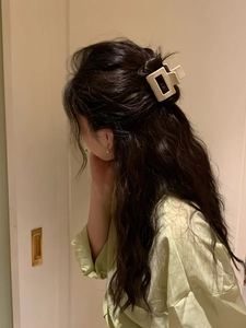 Detail of a beige acetate rectangular claw clip securing a half-up hairstyle